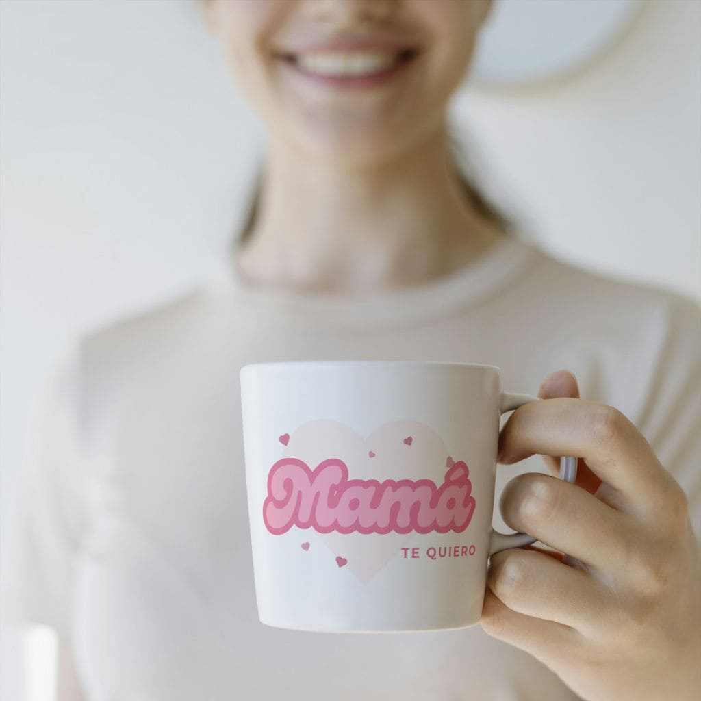 Persona sonriendo sosteniendo en su mano la taza mamá te quiero de Canella en Rama
