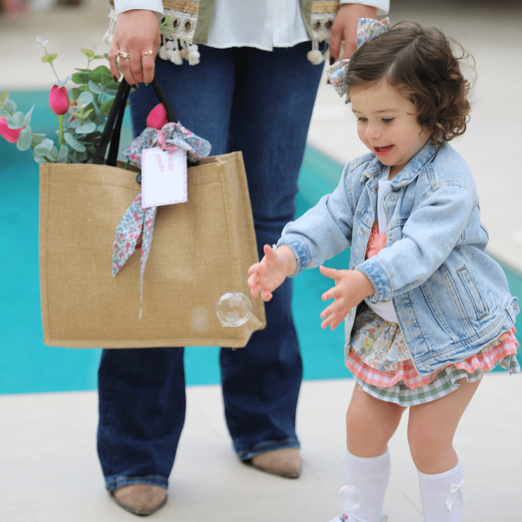 Niña cogiendo burbuja con el bolso día de la madre de Canella en Rama de fondo