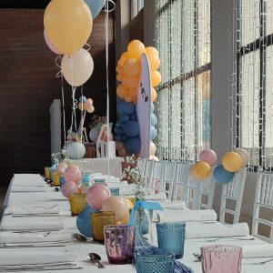 Mesa de niños para comunión con globos y en el fondo la mesa dulce para comunión de Canella en Rama