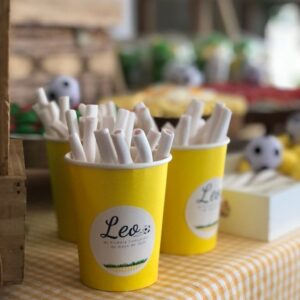 Vasos amarillos con palos de chuches de la mesa dulce de comunión