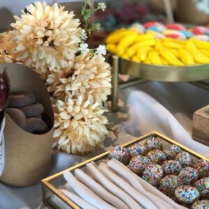 Detalle de decoración floral y chuches dispuestos en mesa dulce dorada para boda, con tonos naturales y elegantes