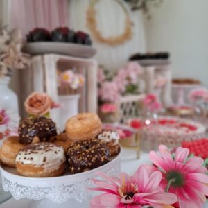 Mesa dulce floral para boda con donuts decorados en tonos pastel y detalles florales en tonos rosados.