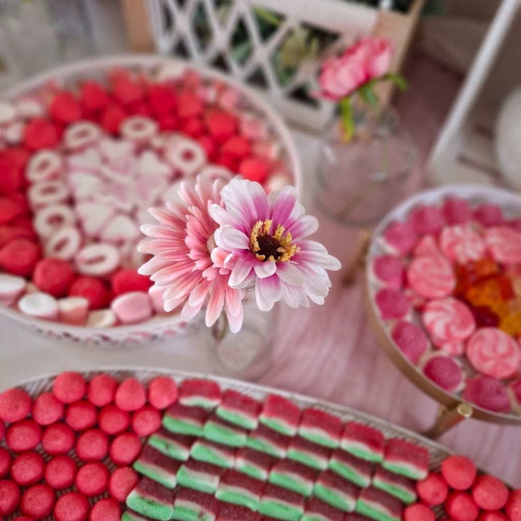 Detalle de flores y chuches en tonos rosados en la mesa dulce floral para boda.