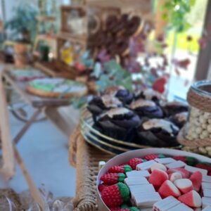 Mesa dulce rústica con muffins, chuches rojas y verdes en decoración natural para bodas