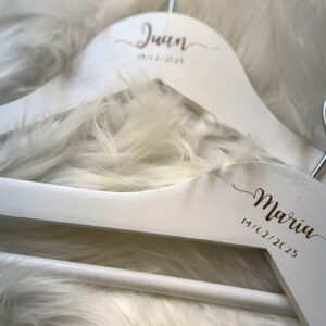 Detalle de perchas personalizadas para novios con grabado de nombres y fecha del día de la boda.