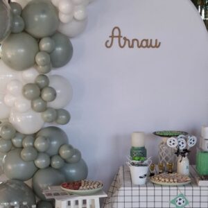 Mesa dulce de fútbol con globos verdes y blancos, nombre personalizado "Arnau" en madera y decoración temática.