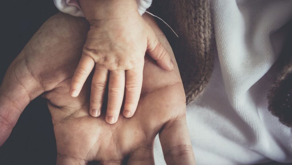 Foto perfil de la mano del hijo sobre la mano de su padre