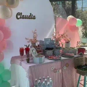 Mesa dulce de comunión en tonos pastel con globos, detalles elegantes y dulces variados para una celebración especial.