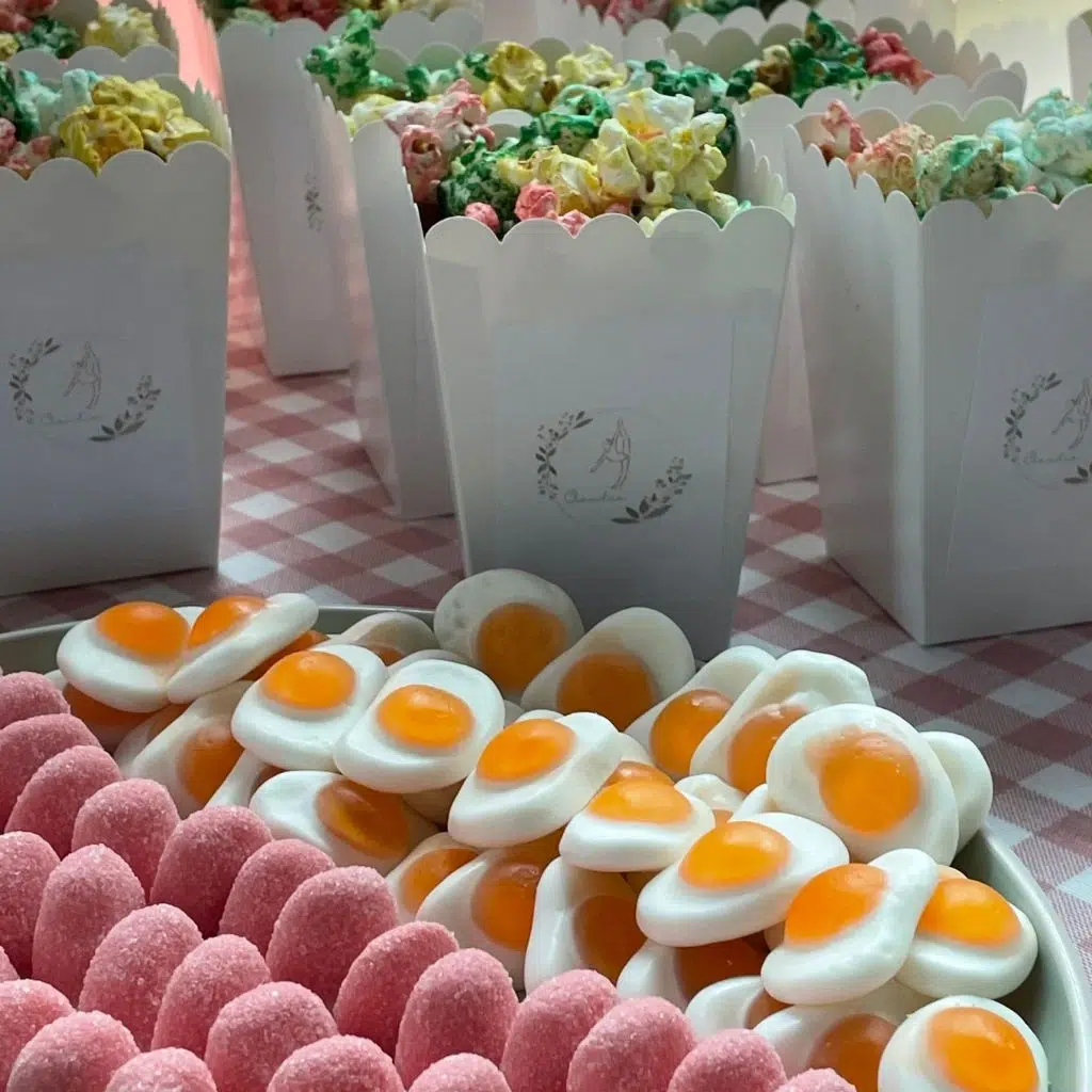 Detalle de la mesa dulce de comunión con chuches en tonos pastel, bandejas decorativas y accesorios elegantes.