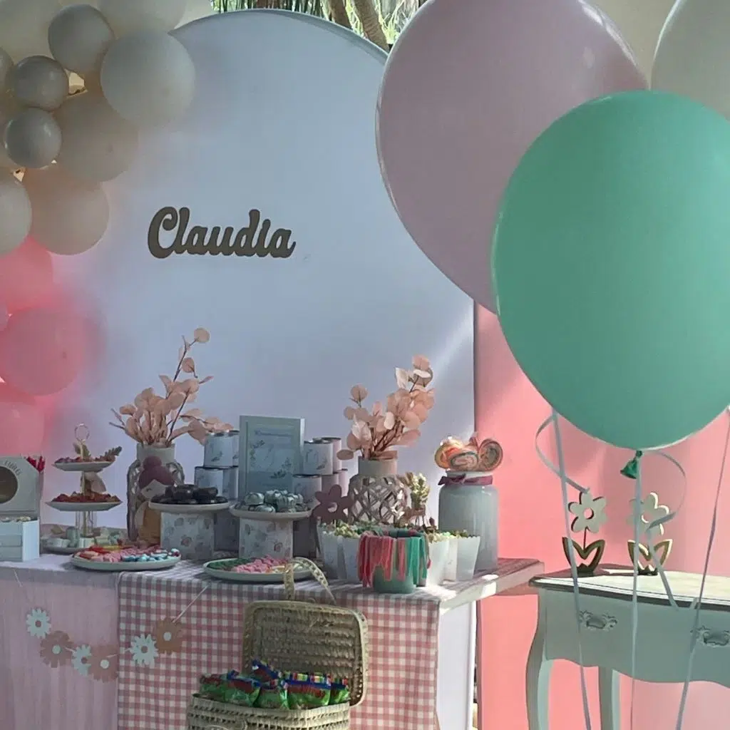 Vista lateral de la mesa dulce de comunión elegante, con dulces coloridos y detalles en rosa y verde menta.
