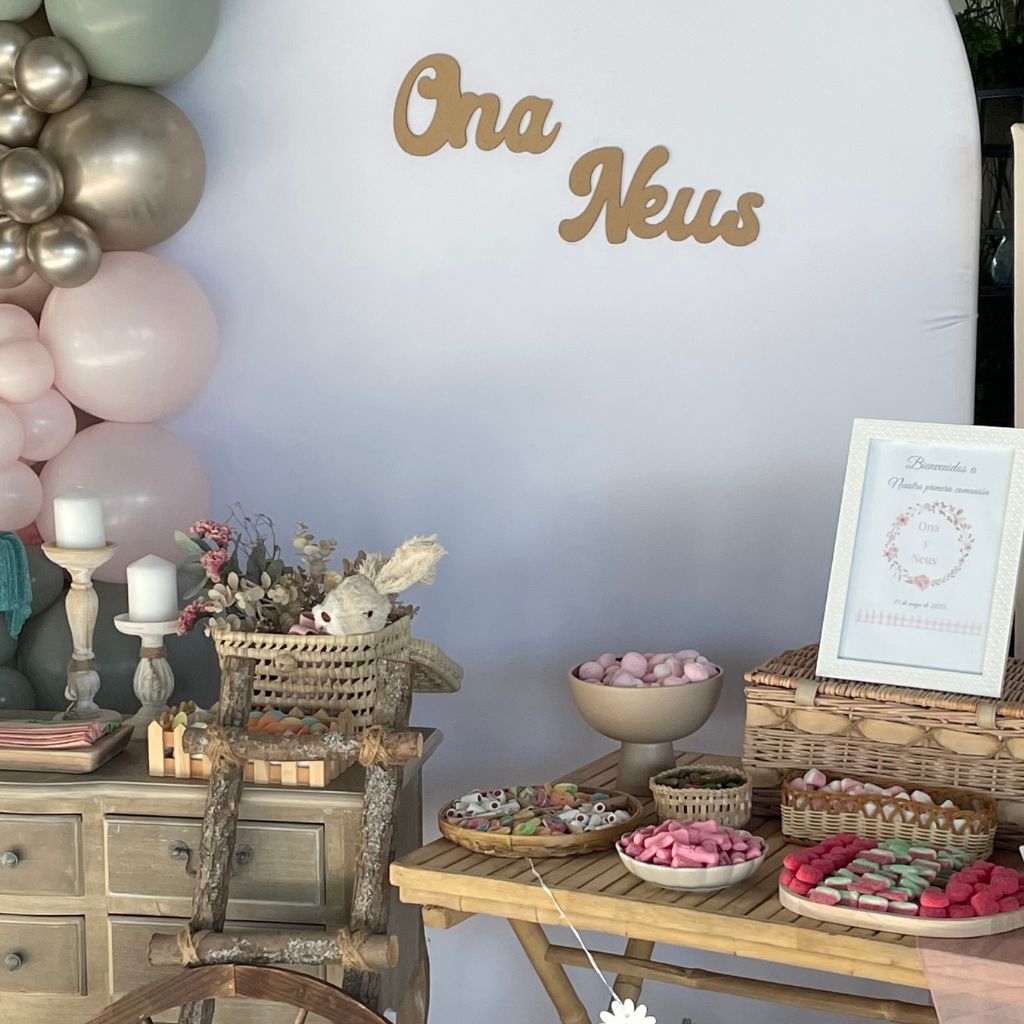 Mesa dulce de comunión elegante y rústica con dulces coloridos, fondos en tonos suaves y decoración floral encantadora.