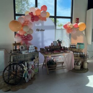 Mesa dulce de conejito con decoración en tonos menta y beige, globos pastel y chuches variadas.