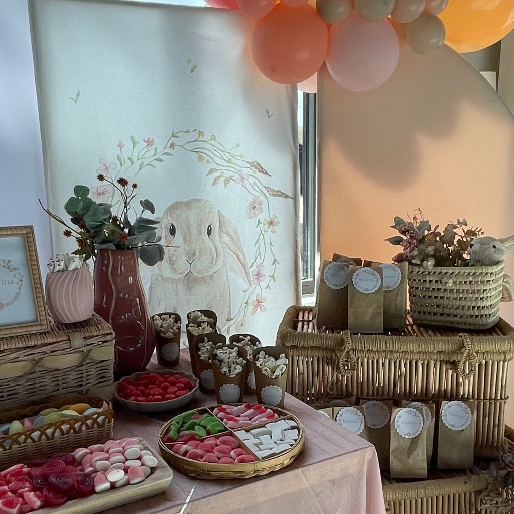Detalle de mesa dulce temática con conejito, dulces personalizados y decoración rústica con flores secas.
