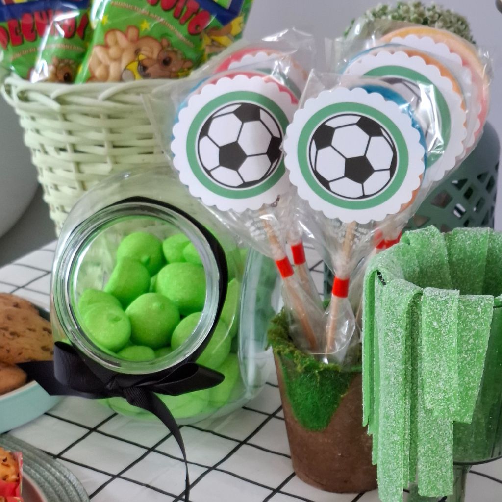 Detalle de chuches temáticas de fútbol: piruletas personalizadas, nubes verdes, tiras de azúcar y snacks.