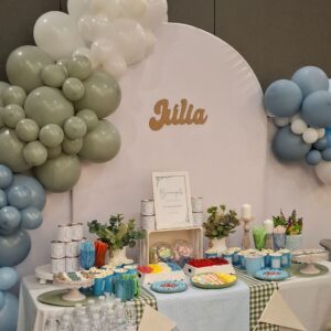 Mesa dulce para primera comunión decorada en tonos azul, blanco y verde con globos y dulces variados.