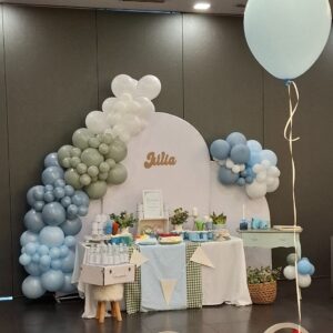 Vista general de la mesa dulce para primera comunión con fondo con nombre, arco de globos y dulces en tonos suaves