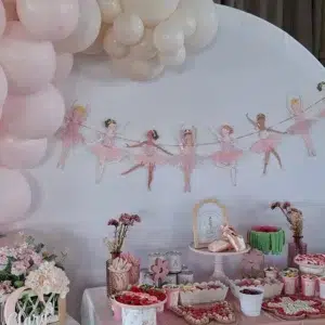 Detalle de la mesa dulce de bailarina con guirnalda de bailarinas, zapatillas de ballet y decoración floral.
