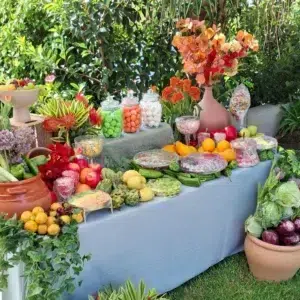Mesa dulce tropical con frutas frescas, golosinas y decoración floral en un entorno natural