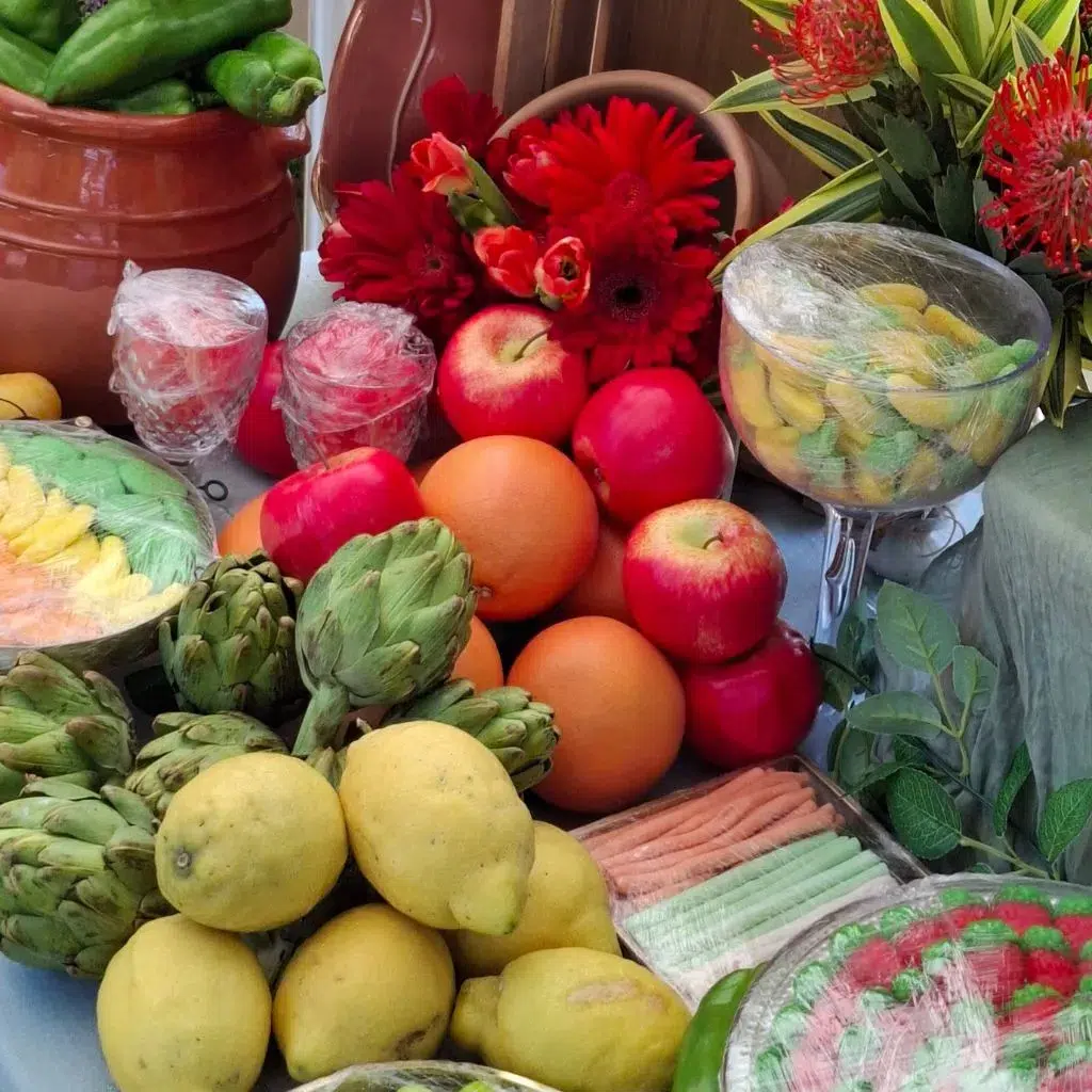 Vista frontal de la mesa dulce tropical con variedad de frutas, chuches en tarros de cristal y flores exóticas