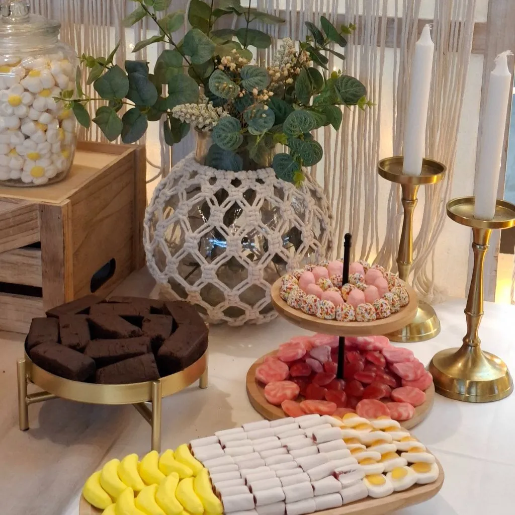 Detalle de bandejas con chuches, brownies y decoración de macramé en mesa dulce estilo Ibiza