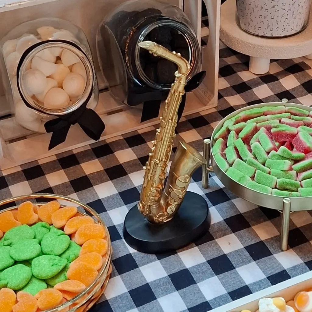 etalle de saxofón decorativo en mesa dulce temática de música con chuches verdes y naranjas.